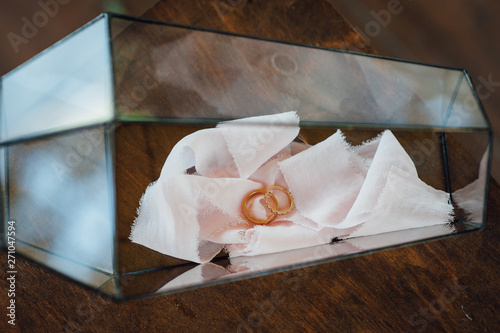 Two gold wedding rings in an elegant glass box.