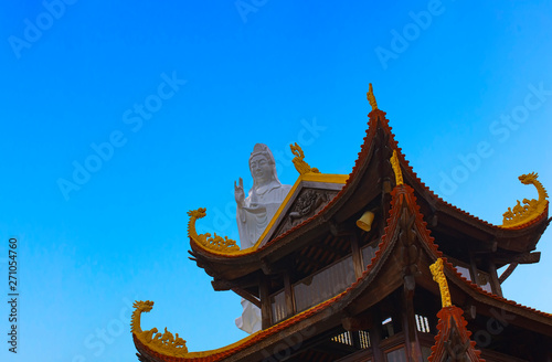 CloseUp of Ho Quoc Pagoda and big white Buddha statue on the blue sky. The biggest ancient Buddhist temple in Phu Quoc Island, Vietnam. Religion and travel concept.