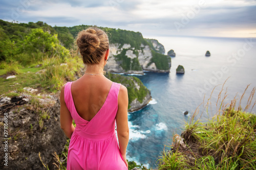  woman sitting on the edge of a cliff and looking at sunset, Nusa Penida