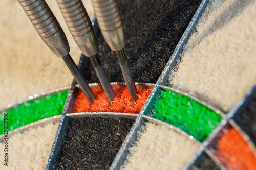 Close up view on three darts in triple twenty sector of sisal dartboard