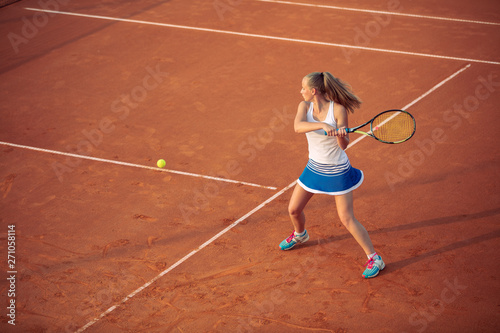 Woman playing tennis on clay court, with sporty outfit and healthy lifestyle © FS-Stock