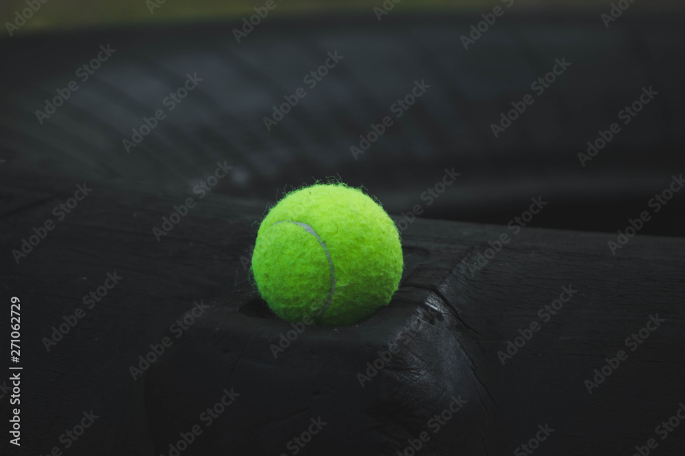 tennis ball lying on the rubber wheel at the sports field