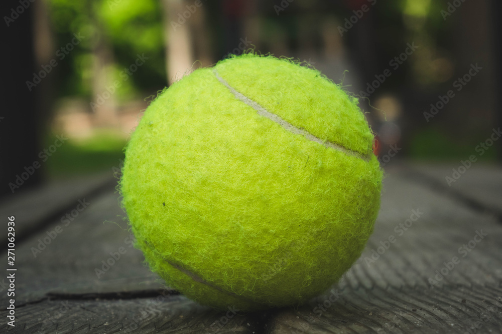 yellow tennis ball with a racket on the street court