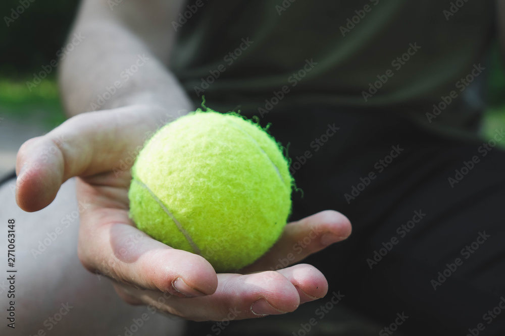 man holding a green tennis ball in the street
