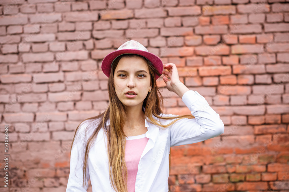 close up portrait of beautiful stylish kid girl in hat near pink brick wall as background close up portrait of beautiful stylish kid girl in hat near pink brick wall as background