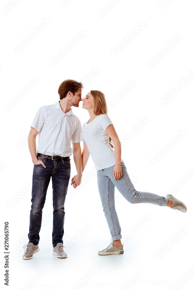 Beautiful young couple in casual clothing flirting, white background