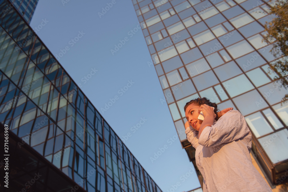 Fototapeta premium business, communication, technology and people concept - young smiling african american businesswoman calling on smartphone in city