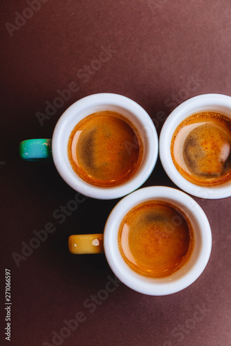 Threee colorfull cups of espresso coffee on dark background