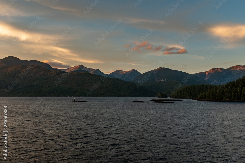 The view at sunset from the side of a ferry as it makes its way through the Inside Passage off the rugged west coast of Canada, the light fading in the distance, nobody in the image