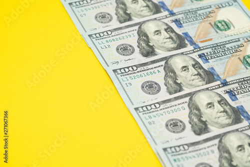 US one hundred dollars bills money on yellow background, close up photo