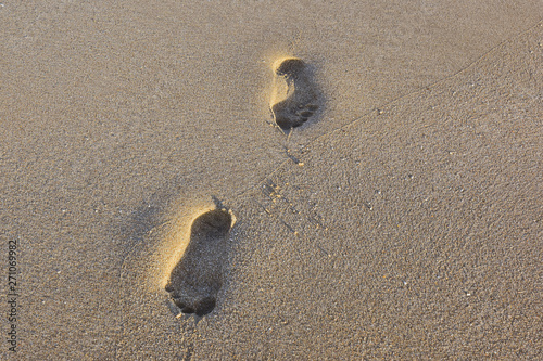 Obraz na płótnie two human footprints in the fine sand at sunset w salonie