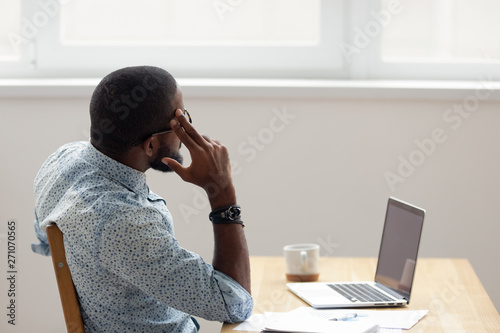 Thoughtful African American businessman looking out window sitting at office