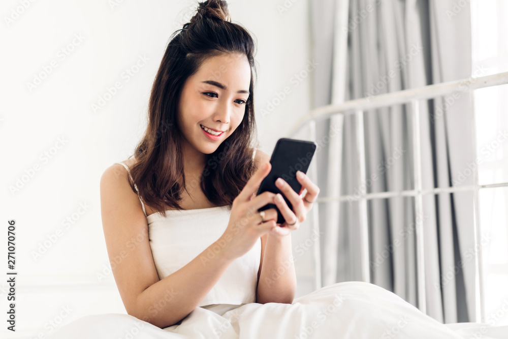 Happy woman relaxing using and talking by smartphone on the bed at home.technology and communication concept Happy woman relaxing using and talking by smartphone on the bed at home.technology and communication concept