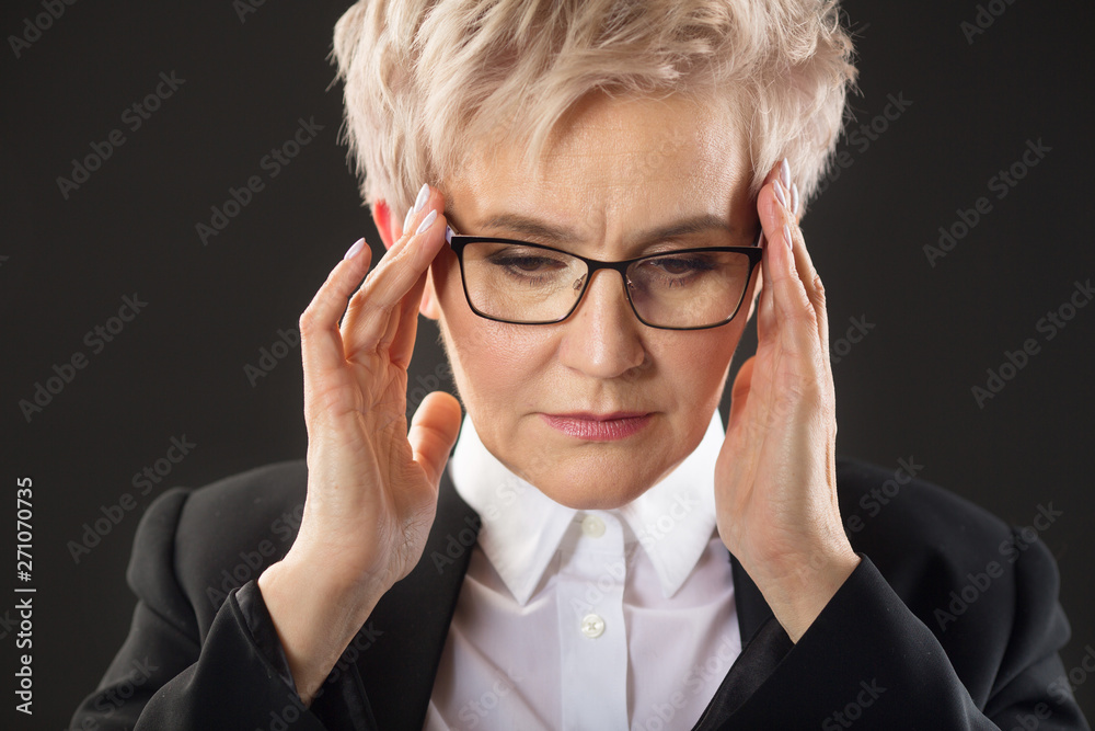 Stylish elderly woman in glasses and in a black jacket on a black background with expression on her face Stylish elderly woman in glasses and in a black jacket on a black background with expression on her face