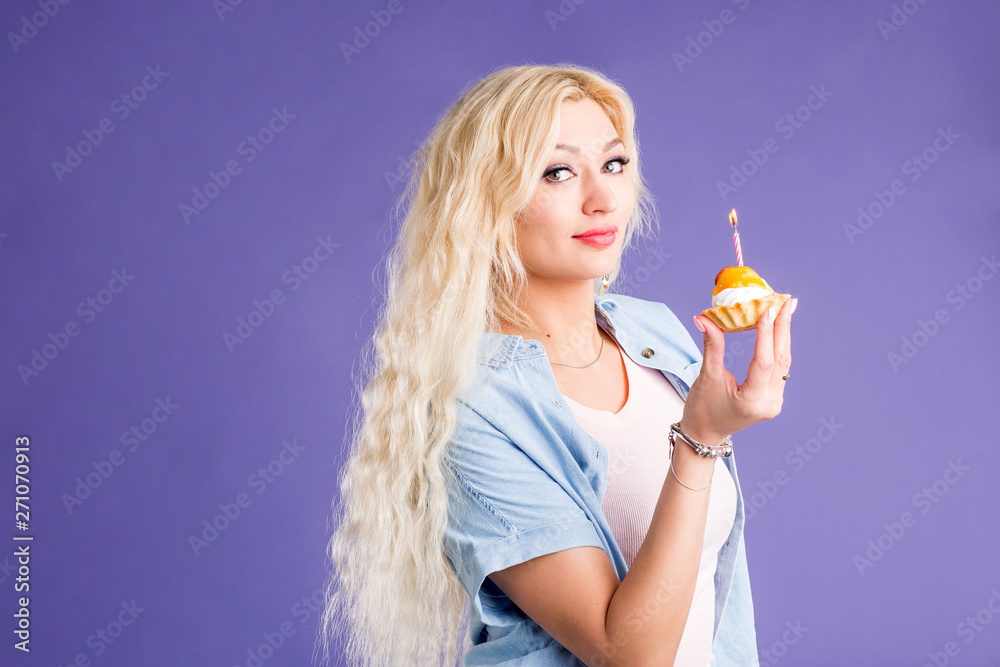 Happy lovely curly young woman holding birthday cupcake with candle Happy lovely curly young woman holding birthday cupcake with candle