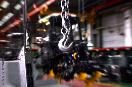 Crane hook of the overhead crane in the workshop of an industrial plant for the production of tractors and agricultural harvesters. Motion blur effect. Background inside of the industrial factory