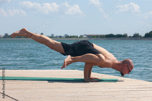 Man doing yoga on a wooden floor in the nature