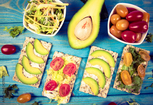 Healthy snack from wholegrain rye crispbread cracker with cherry tomatoes, avocado and salad. Proper nutrition. photo