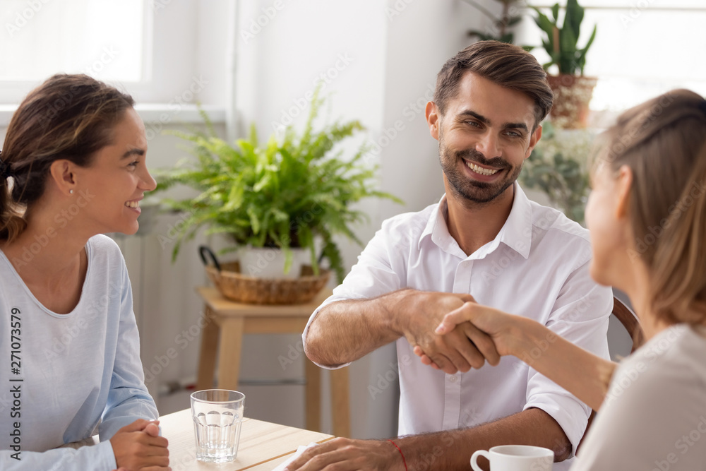 Smiling caucasian male manager, partner shaking hands thanking coworker