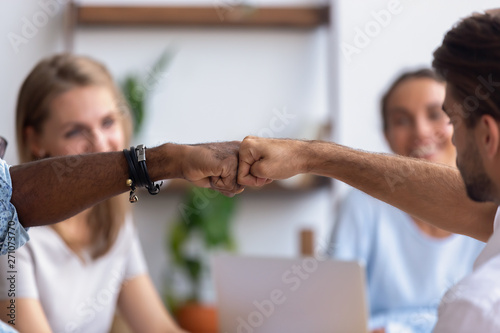 Close up diverse male hands, colleagues giving fist bump