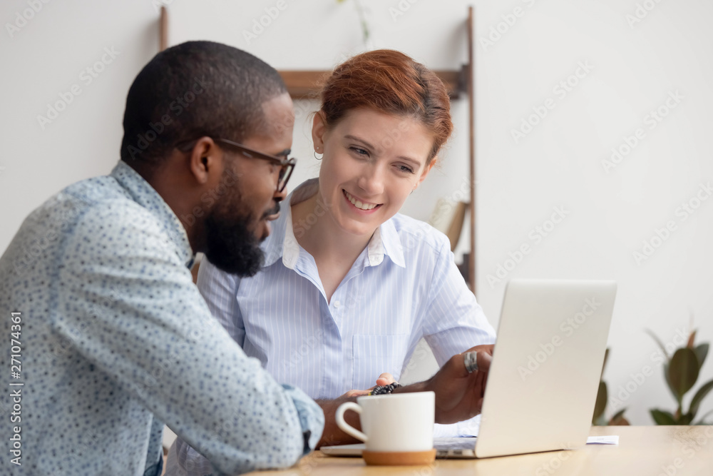 Two diverse smiling businesspeople discussing online project Two diverse smiling businesspeople discussing online project