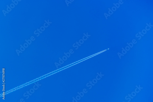 ..Airplane with contrail in the blue sky. The concept of freedom  moving forward. Sky background