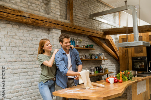 Young couple caking pizza in kitchen together
