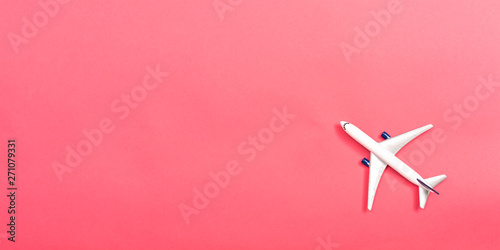 A toy airplane on a pink paper background
