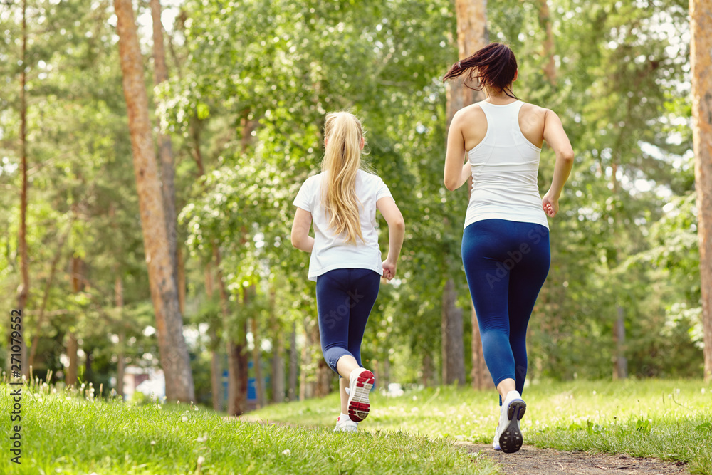 running sporty mother and daughter. woman and child jogging in park. outdoor sports and fitness family running sporty mother and daughter. woman and child jogging in park. outdoor sports and fitness family