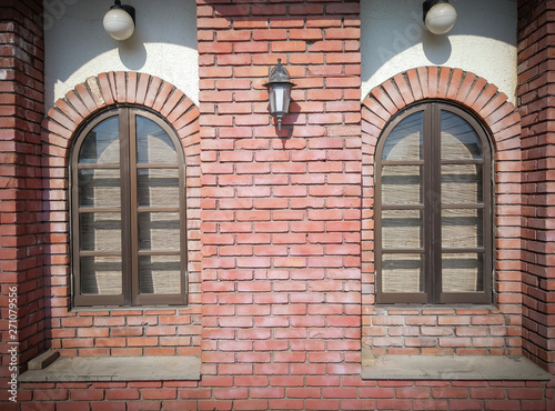 Front view of two vintage rounded window on weathered red brick blocks wall background.