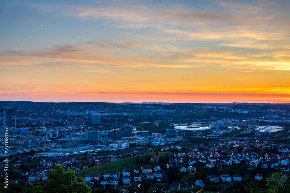 Fototapeta premium Germany, Red sky over houses of major city stuttgart downtown skyline and popular arena in summer from above