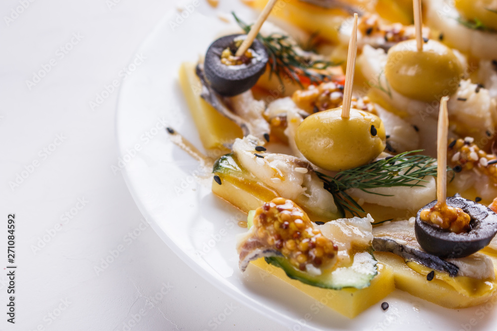 Salted herring on skewers with cheese and olives on plate Salted herring on skewers with cheese and olives on plate