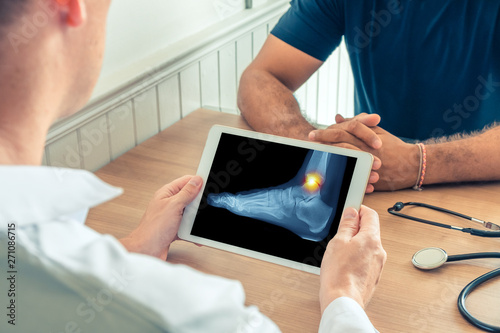 Doctor holding a digital tablet with x-ray of foot of the patient. Pain on the ankle