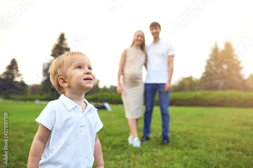 A boy with a toy on the background of parents in the park.