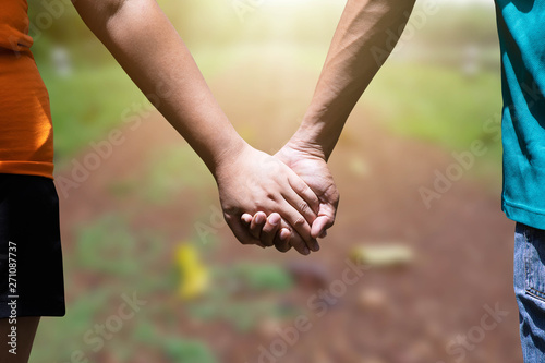 Man and woman holding hand on blurred green nature background