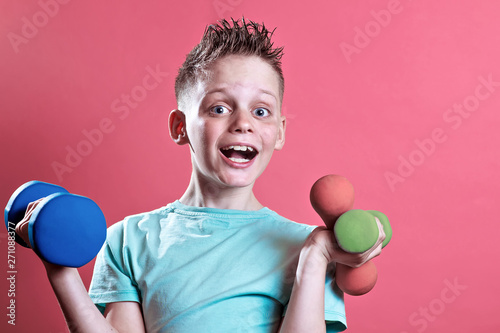 a boy in a bright t-shirt with dumbbells on a yellow background