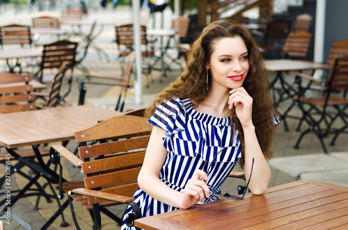 Happy pensive woman  in a coffee shop terrace in the street