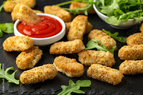 Fried mozzarella cheese sticks in breadcrumbs with ketchup sauce and wild rocket leaves
