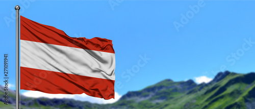 Austria flag waving in the blue sky with green fields at mountain peak background. Nature theme. photo