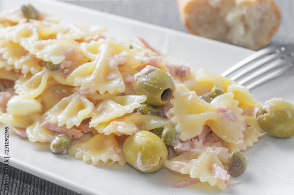 An italian pasta dish (farfalle type) topped with tuna capers and olives