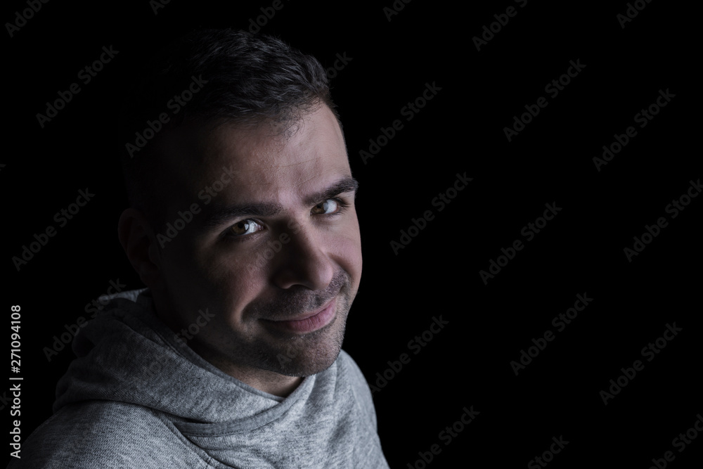 Side studio portrait of a caucasian man looking at the camera. Isolated on black background. Closeup. Horizontal. Copyspace.