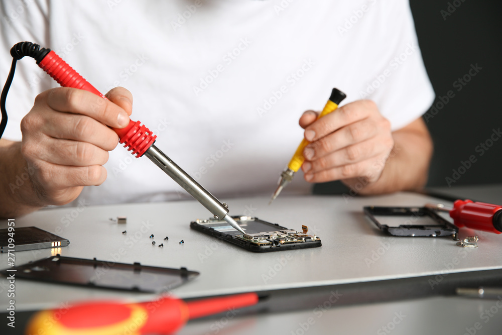 Technician repairing mobile phone at table, closeup Technician repairing mobile phone at table, closeup