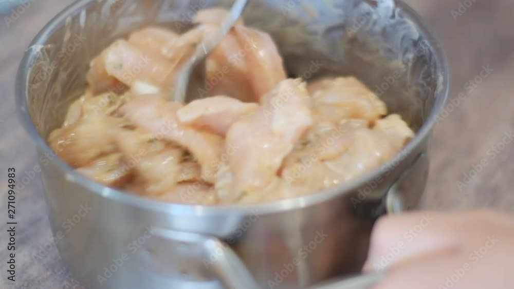 stirring a spoonful of chicken breast pieces in a saucepan with marinade stirring a spoonful of chicken breast pieces in a saucepan with marinade