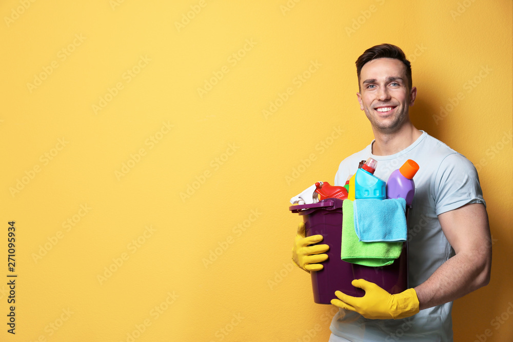 Man with bucket of detergents on color background. Space for text Man with bucket of detergents on color background. Space for text