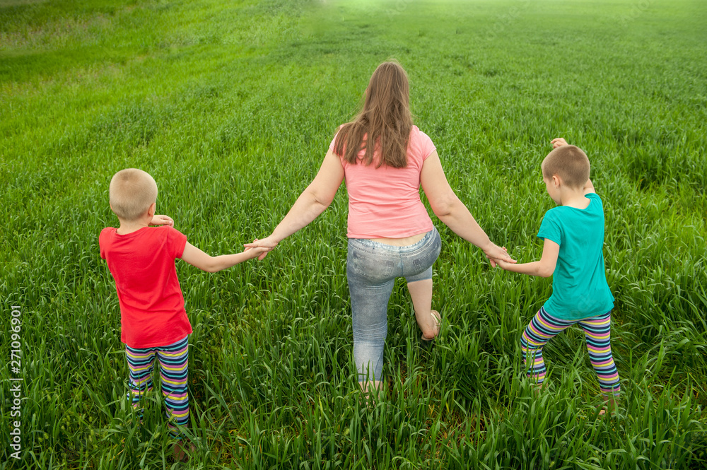 Happy mother with children playing on a green field with wheat..Unity with nature concept Happy mother with children playing on a green field with wheat..Unity with nature concept