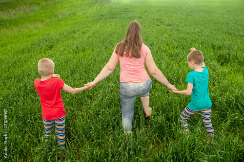 Happy mother with children playing on a green field with wheat..Unity with nature concept © galitsin