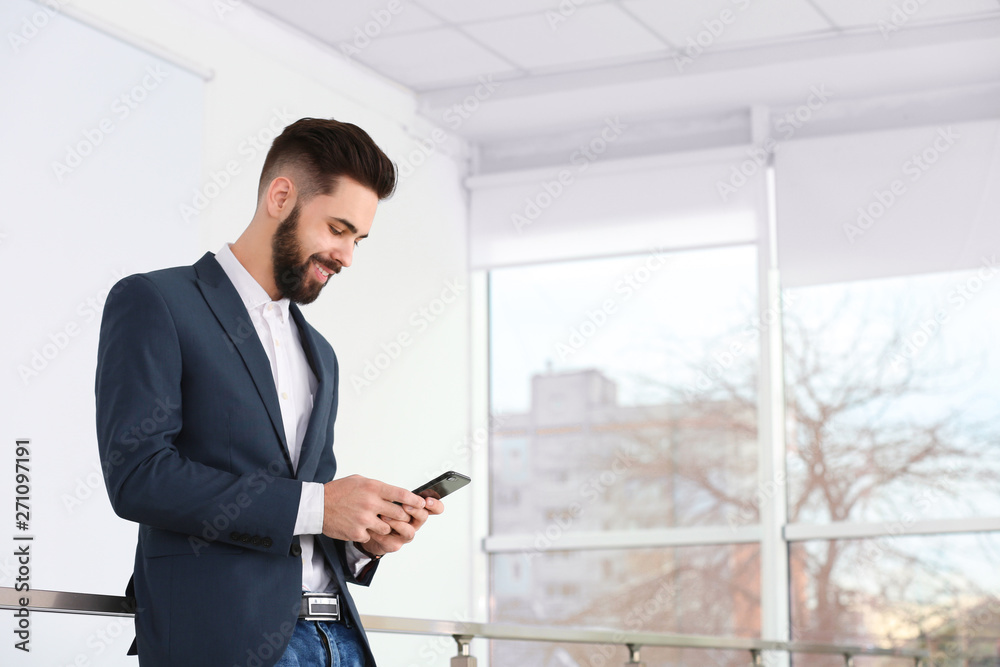 Handsome young man using phone in light room. Working time Handsome young man using phone in light room. Working time