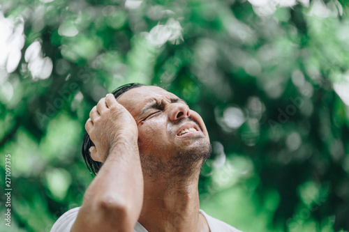 portrait young Asian man in raising head up and looking at sky during the rain