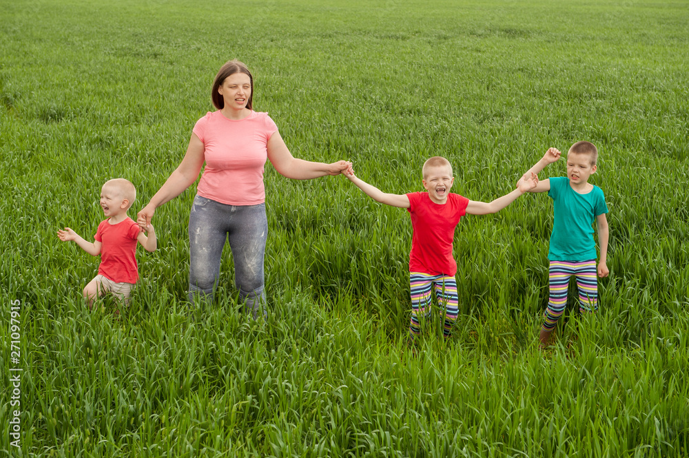 Happy mother with children playing on a green field with wheat..Unity with nature concept Happy mother with children playing on a green field with wheat..Unity with nature concept