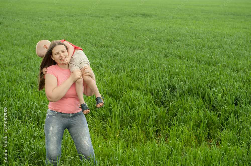 Happy mother with children playing on a green field with wheat..Unity with nature concept Happy mother with children playing on a green field with wheat..Unity with nature concept